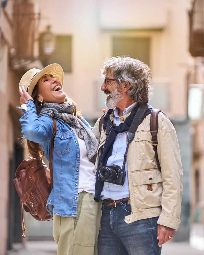 Casal mais velho rindo numa rua de cidade histórica